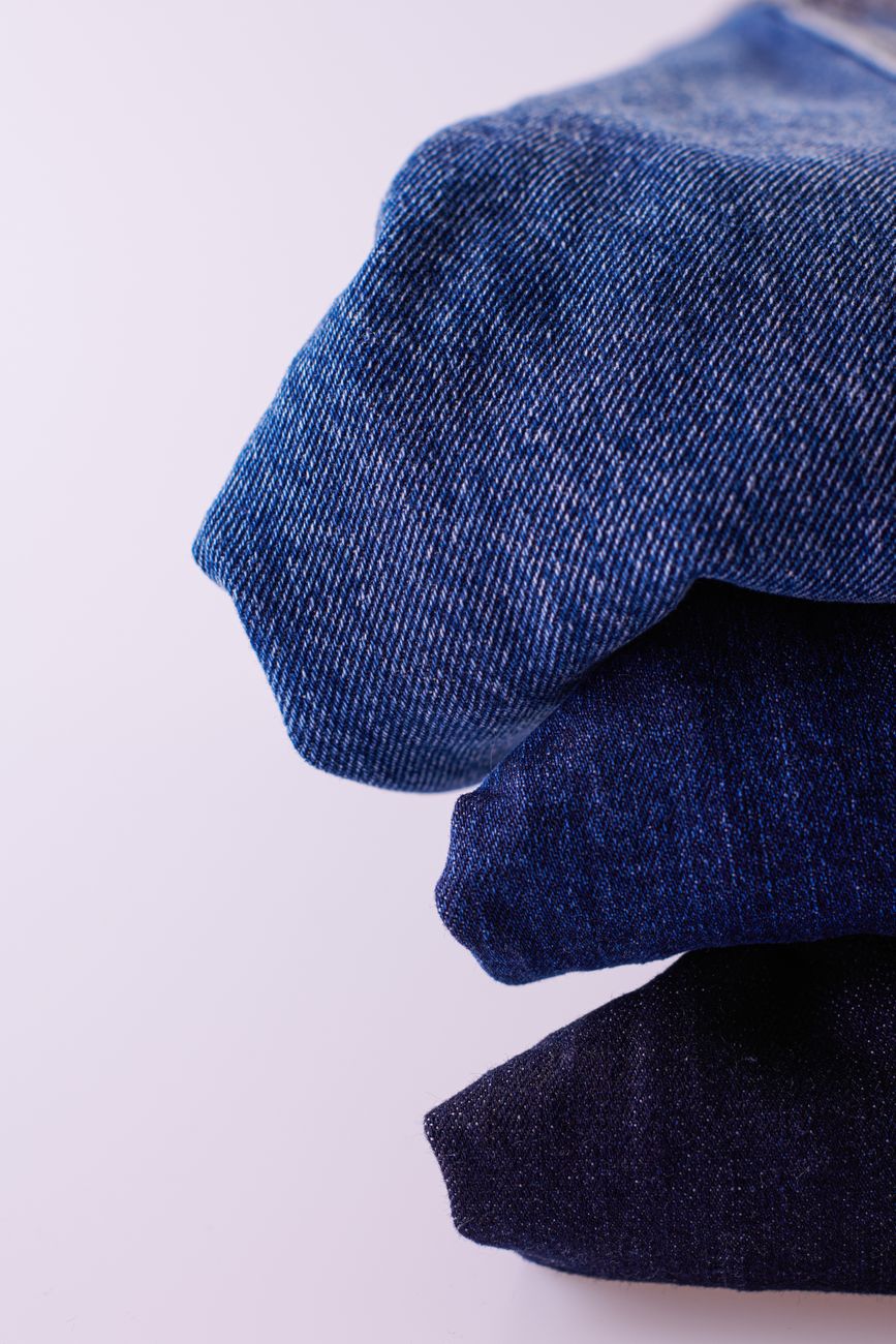 Pila de jeans azules doblados sobre fondo blanco con distintos tonos